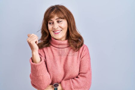 Photo for Middle age hispanic woman standing over isolated background smiling with happy face looking and pointing to the side with thumb up. - Royalty Free Image