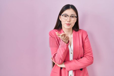 Téléchargez les photos : Chinois affaires jeune femme portant des lunettes regardant la caméra souffler un baiser avec la main sur l'air étant belle et sexy. expression d'amour. - en image libre de droit