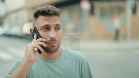 Téléchargez les photos : Young hispanic man talking on smartphone with serious expression at street - en image libre de droit