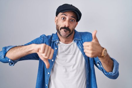 Photo for Hispanic man with beard standing over isolated background doing thumbs up and down, disagreement and agreement expression. crazy conflict - Royalty Free Image