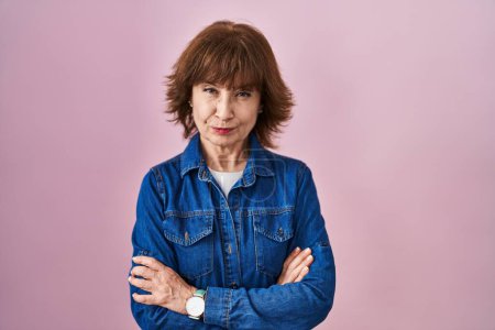 Photo for Middle age woman standing over pink background skeptic and nervous, disapproving expression on face with crossed arms. negative person. - Royalty Free Image