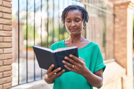 Téléchargez les photos : Moyen Age femme afro-américaine lecture livre à la rue - en image libre de droit