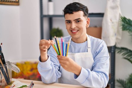 Photo for Young non binary man artist smiling confident holding color pencils at art studio - Royalty Free Image