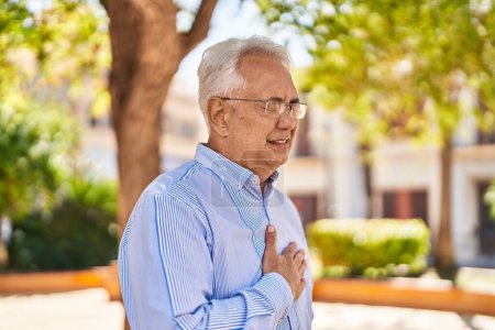 Téléchargez les photos : Homme âgé touchant le cœur avec une expression inquiète au parc - en image libre de droit