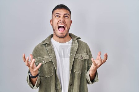 Photo for Young hispanic man standing over isolated background crazy and mad shouting and yelling with aggressive expression and arms raised. frustration concept. - Royalty Free Image