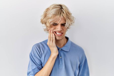 Téléchargez les photos : Jeune homme moderne debout sur fond isolé touchant la bouche avec la main avec une expression douloureuse à cause de maux de dents ou de maladies dentaires sur les dents. dentiste - en image libre de droit
