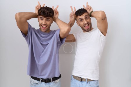 Photo for Homosexual gay couple standing over white background posing funny and crazy with fingers on head as bunny ears, smiling cheerful - Royalty Free Image