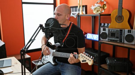 Téléchargez les photos : Jeune homme hispanique musicien chantant une chanson jouant de la guitare électrique au studio de musique - en image libre de droit
