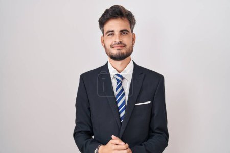 Photo for Young hispanic man with tattoos wearing business suit and tie with hands together and crossed fingers smiling relaxed and cheerful. success and optimistic - Royalty Free Image