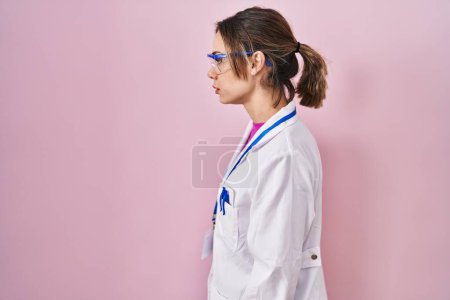 Photo for Hispanic woman wearing scientist uniform looking to side, relax profile pose with natural face with confident smile. - Royalty Free Image