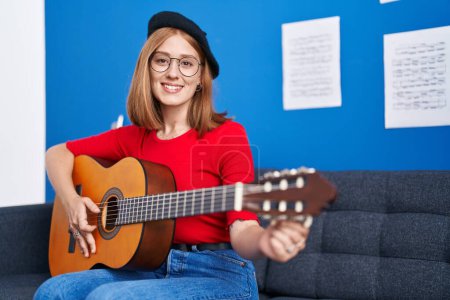 Photo for Young redhead woman musician smiling confident playing classical guitar at music studio - Royalty Free Image