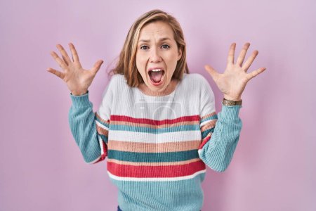 Photo for Young blonde woman standing over pink background celebrating crazy and amazed for success with arms raised and open eyes screaming excited. winner concept - Royalty Free Image