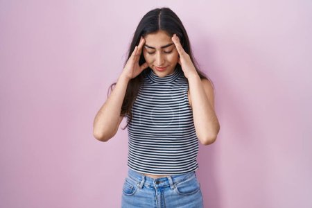 Foto de Joven adolescente con camiseta de rayas casuales con la mano en la cabeza para el dolor en la cabeza porque el estrés. padecer migraña. - Imagen libre de derechos