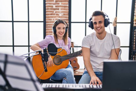 Photo for Man and woman musicians playing piano and spanish guitar at music studio - Royalty Free Image