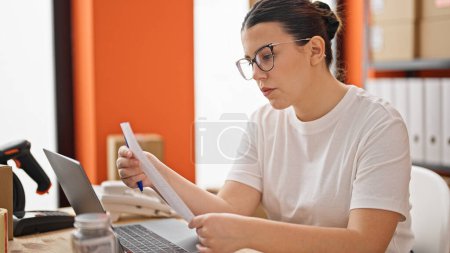 Photo for Young beautiful hispanic woman ecommerce business worker reading finances at the office - Royalty Free Image