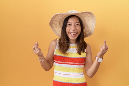 Photo for Middle age chinese woman wearing summer hat over yellow background showing middle finger doing fuck you bad expression, provocation and rude attitude. screaming excited - Royalty Free Image