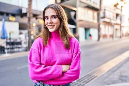 Téléchargez les photos : Jeune femme souriante confiante debout avec les bras croisés geste à la rue - en image libre de droit