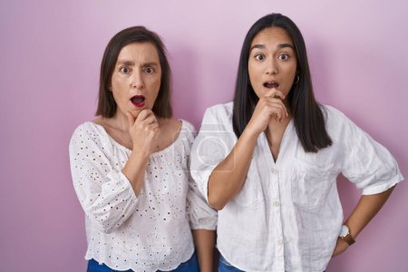 Photo for Hispanic mother and daughter together looking fascinated with disbelief, surprise and amazed expression with hands on chin - Royalty Free Image