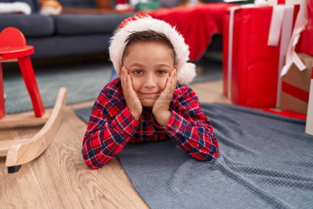 Photo for Adorable hispanic boy smiling confident lying on floor by christmas gifts at home - Royalty Free Image