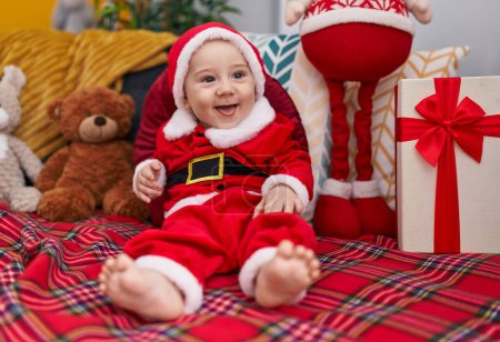 Photo for Adorable caucasian baby wearing christmas costume sitting on sofa at home - Royalty Free Image