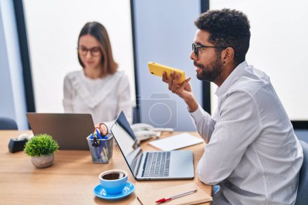 Photo for Man and woman business workers using laptop talking on smartphone at office - Royalty Free Image