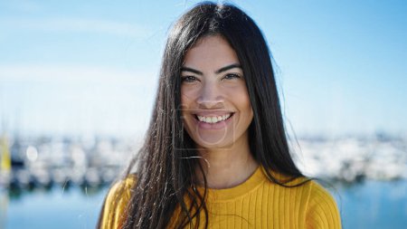Téléchargez les photos : Jeune belle femme hispanique souriant confiance debout au bord de la mer - en image libre de droit