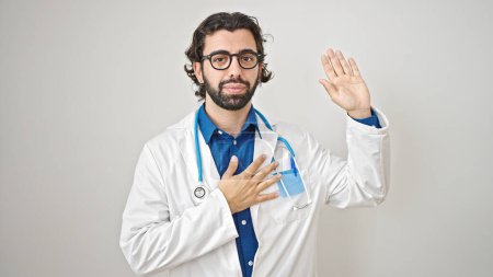 Photo for Young hispanic man doctor making an oath with hand on chest over isolated white background - Royalty Free Image