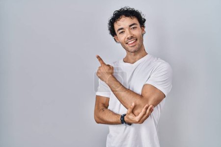 Photo for Hispanic man standing over isolated background with a big smile on face, pointing with hand finger to the side looking at the camera. - Royalty Free Image