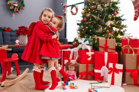 Foto de Adorables chicas abrazándose celebrando la Navidad en casa - Imagen libre de derechos