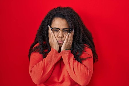 Photo for Plus size hispanic woman standing over red background tired hands covering face, depression and sadness, upset and irritated for problem - Royalty Free Image