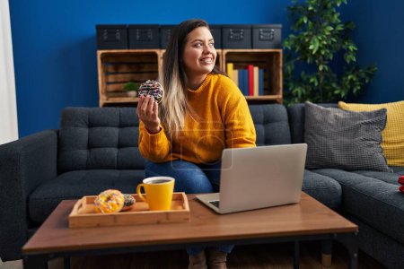 Photo for Young beautiful plus size woman having breakfast using laptop at home - Royalty Free Image