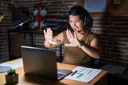 Téléchargez les photos : Jeune femme hispanique travaillant au bureau la nuit faisant un geste d'arrêt avec les paumes des mains, expression de colère et de frustration - en image libre de droit