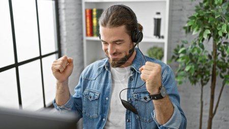 Téléchargez les photos : Jeune homme hispanique travailleur d'affaires en utilisant l'ordinateur et écouteurs célébrant au bureau - en image libre de droit