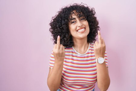 Foto de Young middle east woman standing over pink background showing middle finger doing fuck you bad expression, provocation and rude attitude. screaming excited - Imagen libre de derechos