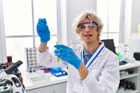 Photo for Young blond man scientist pouring liquid on test tube at laboratory - Royalty Free Image