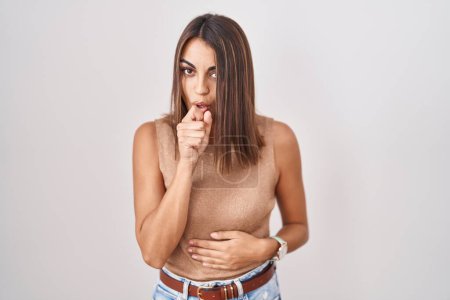 Foto de Young hispanic woman standing over white background feeling unwell and coughing as symptom for cold or bronchitis. health care concept. - Imagen libre de derechos
