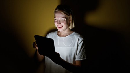 Foto de Mujer rubia joven usando touchpad sonriendo sobre fondo amarillo aislado - Imagen libre de derechos