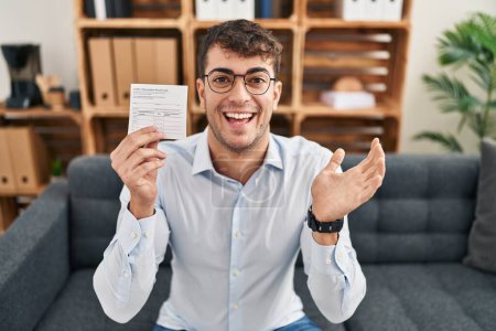 Photo for Young hispanic man holding covid record card celebrating achievement with happy smile and winner expression with raised hand - Royalty Free Image