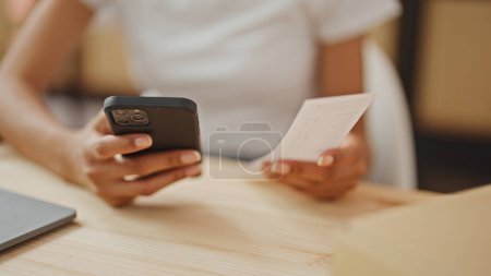 Photo for African american woman ecommerce business worker using smartphone doing ticket account at office - Royalty Free Image