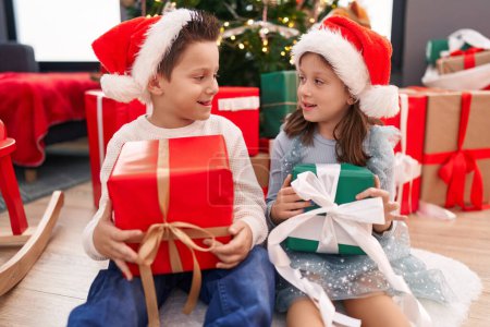 Photo for Adorable boy and girl smiling confident holding christmas gift at home - Royalty Free Image