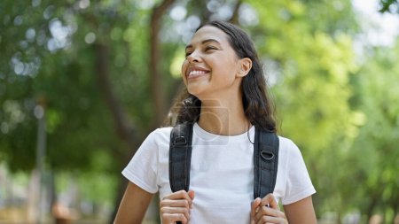 Foto de Turista mujer afroamericana sonriendo confiada usando mochila en el parque - Imagen libre de derechos