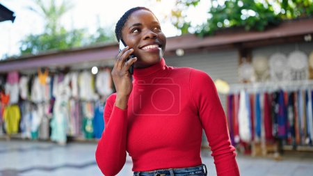 Foto de Mujer afroamericana hablando en smartphone sonriendo en el mercado callejero - Imagen libre de derechos