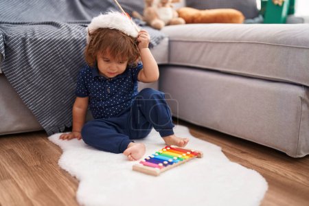 Photo for Adorable hispanic toddler wearing christmas hat playing xylophone at home - Royalty Free Image