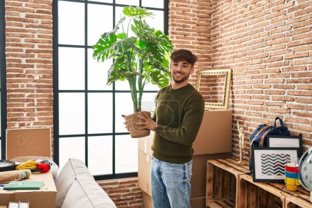 Photo for Young arab man smiling confident holding plant at new home - Royalty Free Image