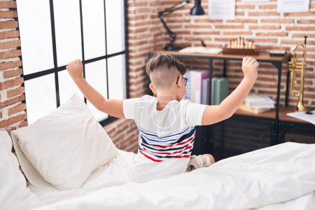 Photo for Adorable hispanic boy waking up stretching arms at bedroom - Royalty Free Image