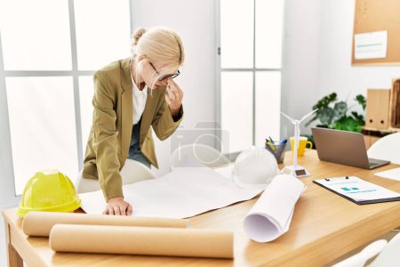Photo for Young blonde woman architect looking house plans stressed at office - Royalty Free Image
