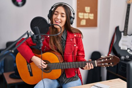 Photo for Young beautiful hispanic woman musician singing song playing classical guitar at music studio - Royalty Free Image