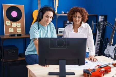 Téléchargez les photos : Deux femmes musiciens composant des chansons à l'aide d'un ordinateur au studio de musique - en image libre de droit
