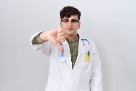 Photo for Young non binary man wearing doctor uniform and stethoscope looking unhappy and angry showing rejection and negative with thumbs down gesture. bad expression. - Royalty Free Image