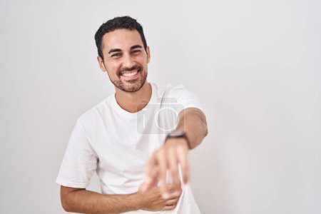 Téléchargez les photos : Bel homme hispanique debout sur fond blanc se moquant de vous, pointant du doigt la caméra avec la main sur le corps, expression de honte - en image libre de droit